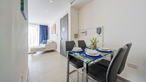 A modern dining area with a glass table, black chairs, and a blue and white table setting. - Stunning Penthouse Apartment With Private Terrace (Gzira)