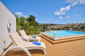A rooftop pool area with lounge chairs and a view of a town. - Sophisticated Grand Villa With Gym and Games Room (Mellieha)