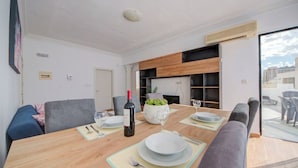 Ein moderner Essbereich mit einem Holztisch, grau gepolsterten Stühlen und einer Zimmerpflanze als Mittelstück.
