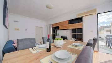 Uma área de jantar moderna com mesa de madeira, cadeiras estofadas cinzas e um vaso de planta como peça central.