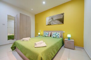 Une chambre à coucher avec une couvre-lit verte, deux lampes de chevet, un tableau au mur et une armoire.