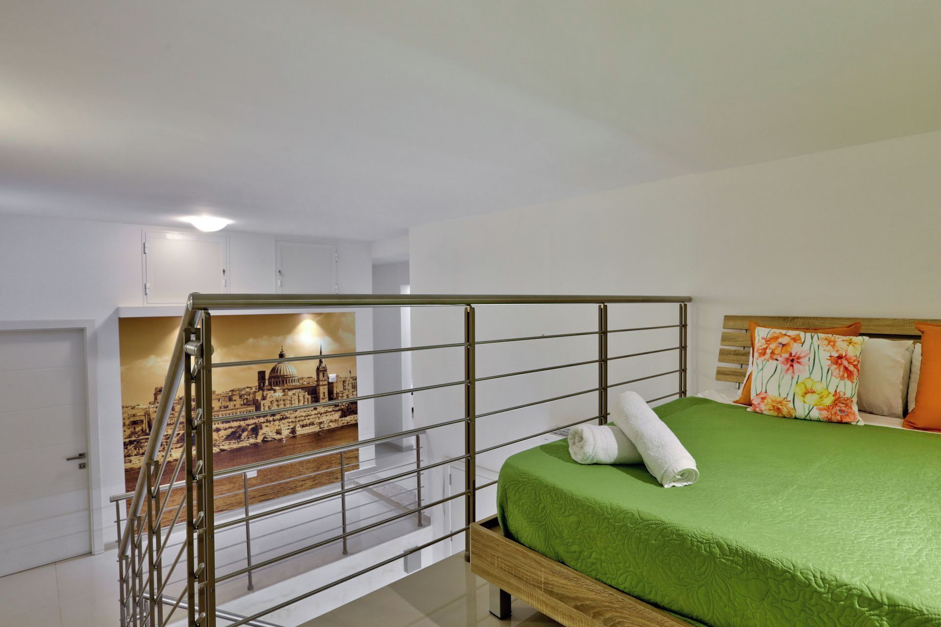 Une chambre à coucher avec un lit, une literie verte, une tête de lit en bois et une vue sur le paysage urbain à travers une cloison en verre.