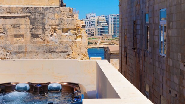Ein Whirlpool auf einem Balkon mit Blick auf eine Skyline und eine Steinmauer.