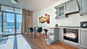 A modern kitchen with a large window, a dining area with chairs, and a view of the city. - Stunning Home Overlooking Valletta City Skyline (Sliema)