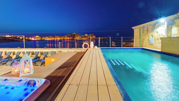 A wooden deck with a pool, lounge chairs, and a hot tub. - Enchanting Stone Villa With Pool and Jacuzzi (Valletta)
