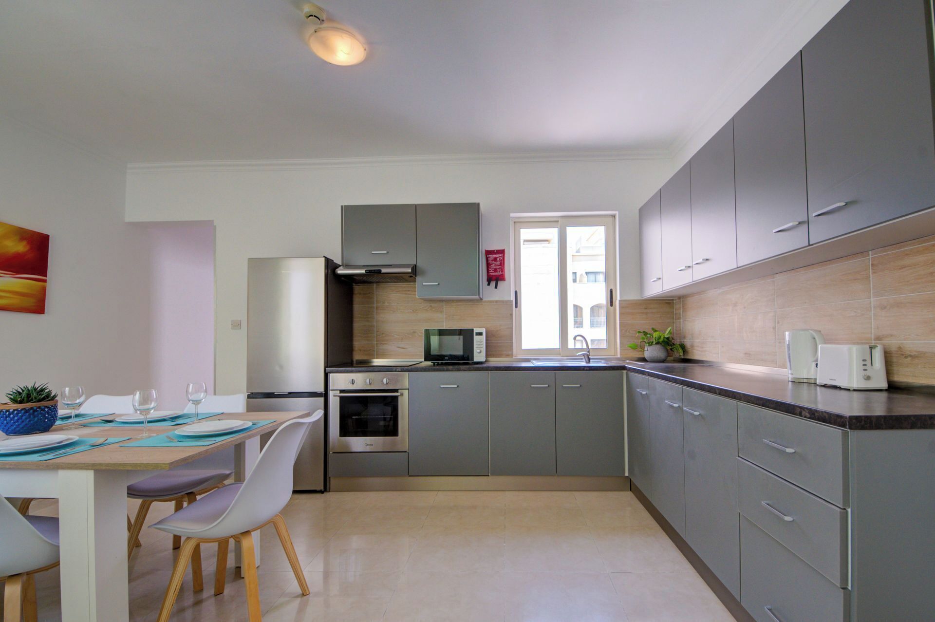 A modern kitchen with grey cabinets, a microwave, an oven, and a sink.