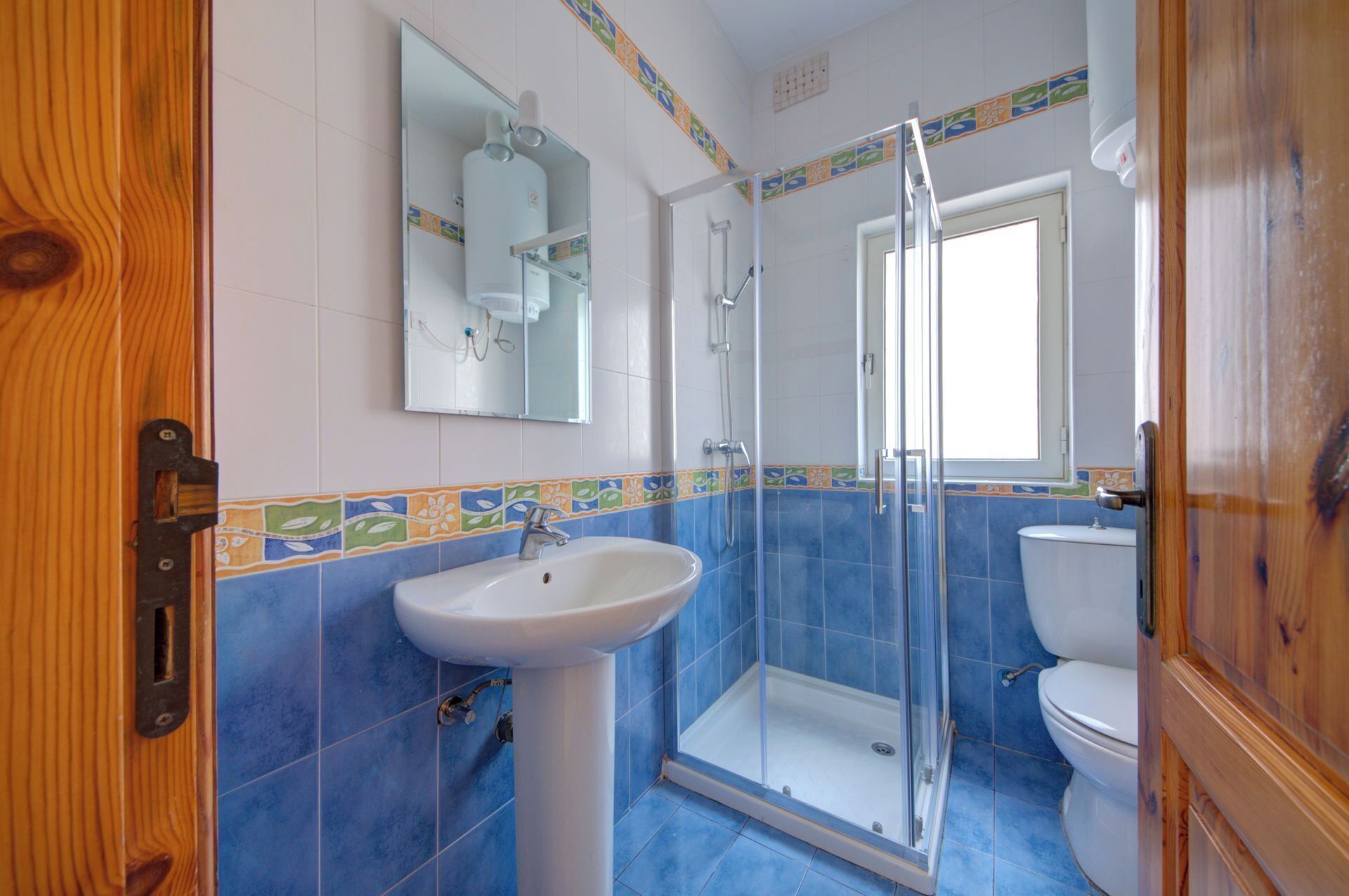 A bathroom with a glass shower enclosure, a white sink, and a toilet.