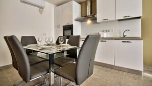 A modern kitchen with white cabinets, a stainless steel range hood, and a built-in oven. - Off the Strand Gzira 3-bedroom Apartment (Gzira)