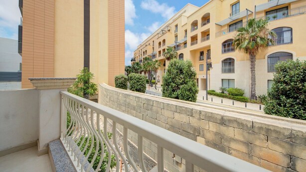 A multi-story hotel with balconies, a stone wall, and palm trees. - Magnificent Minimal Apartment Close to Attractions (St. Julian's)
