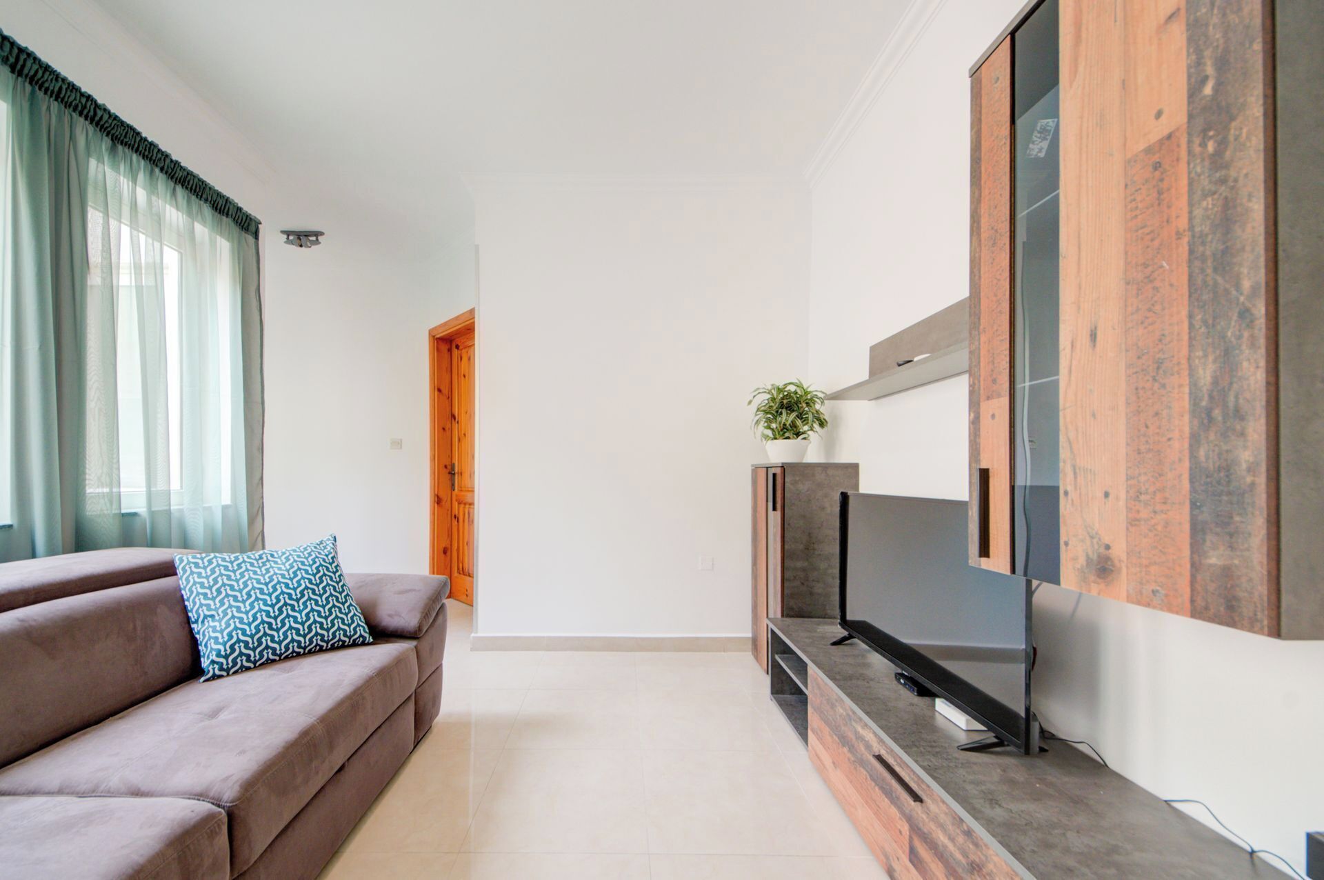 Een moderne woonkamer met een bank, een flatscreen televisie en een houten kast.