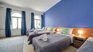 A hotel room with two single beds, a large window with curtains, and a blue accent wall. - Magnificent Minimal Apartment Close to Attractions (St. Julian's)