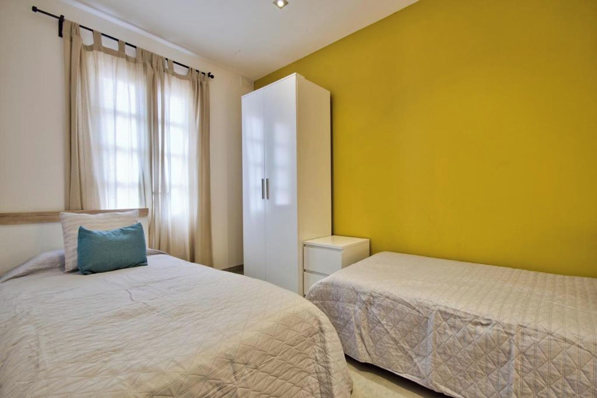 Une chambre avec deux lits, une armoire et une petite table de chevet.