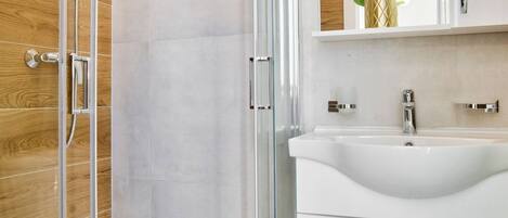 Un bagno moderno con box doccia in vetro, lavabo bianco e parete in legno.