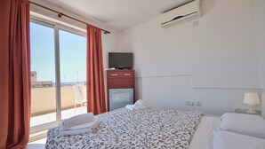 A hotel room with a bed, a TV on a wooden cabinet, and a window with curtains. - Stunning City Views Sliema Duplex Penthouse (Sliema)