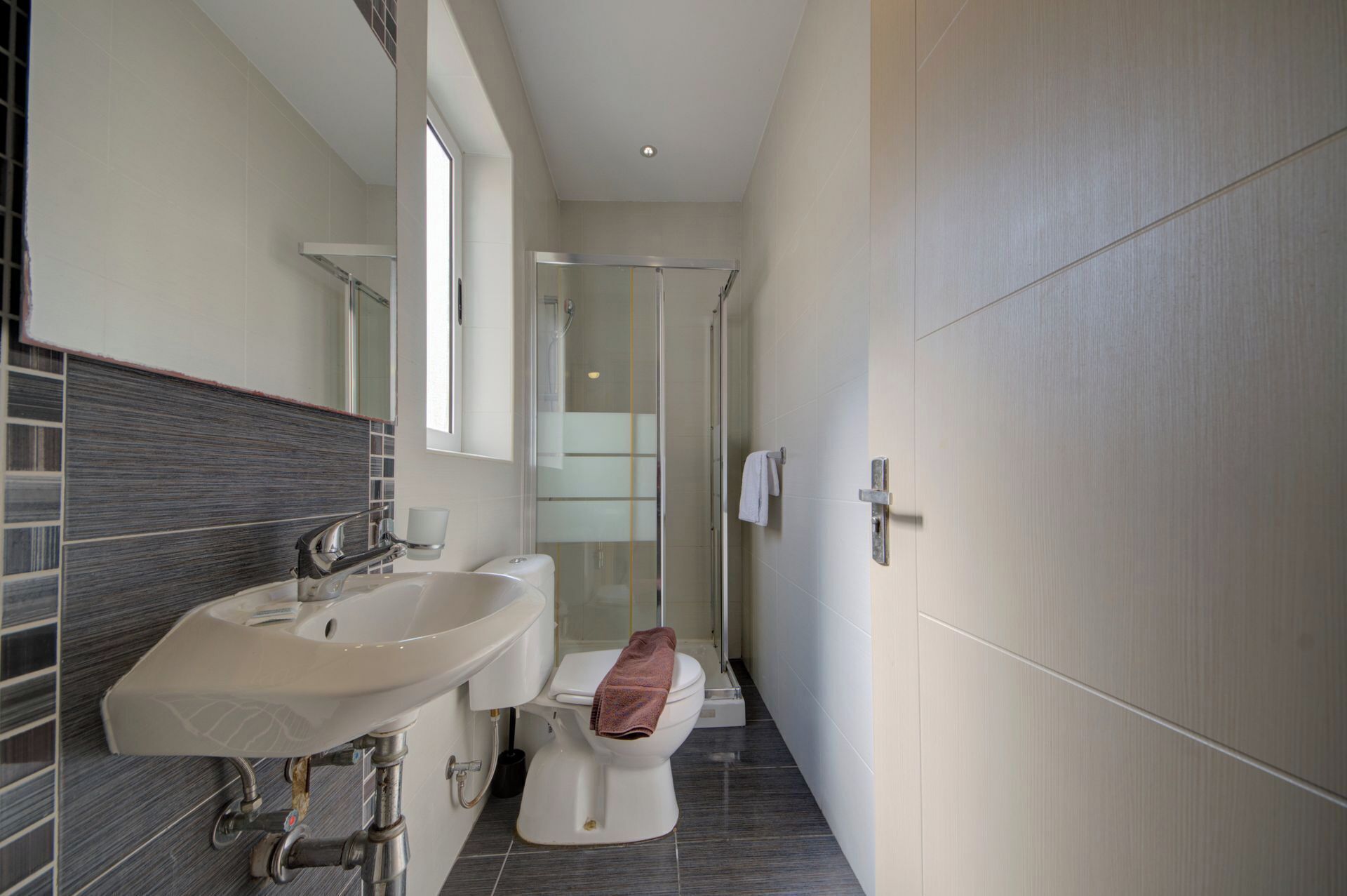 Ein modernes Badezimmer mit einem großen Waschbecken, Toilette und einer Duschkabine aus Glas.