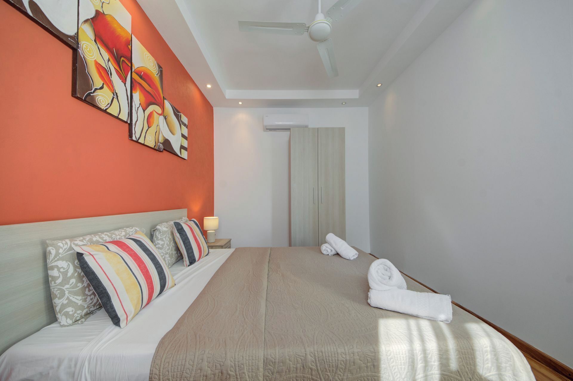 A hotel room with a large bed, a ceiling fan, and artwork on the wall.