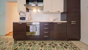 A compact kitchen with a microwave, coffee maker, and oven. - Spacious High Ceiling Sliema Apartment (Sliema)