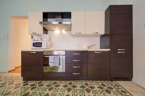 A compact kitchen with a microwave, coffee maker, and oven. - Spacious High Ceiling Sliema Apartment (Sliema)
