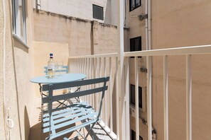 Ein Balkon mit Tisch und Stühlen, einer Wasserflasche und einem Weinglas.