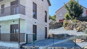 A two-story building with a balcony, a stone wall, and a gravel driveway. - Apartment with shared swimming pool, Sta. (Baiona)