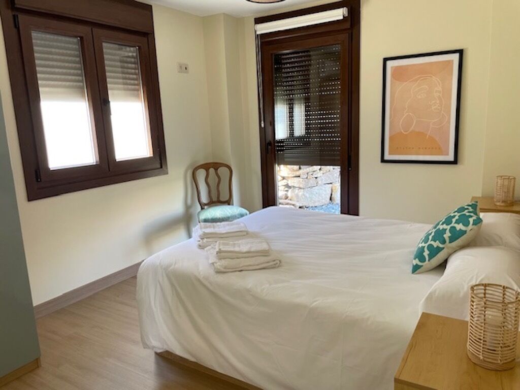 Une chambre à coucher avec un lit, une chaise, une fenêtre et une porte.