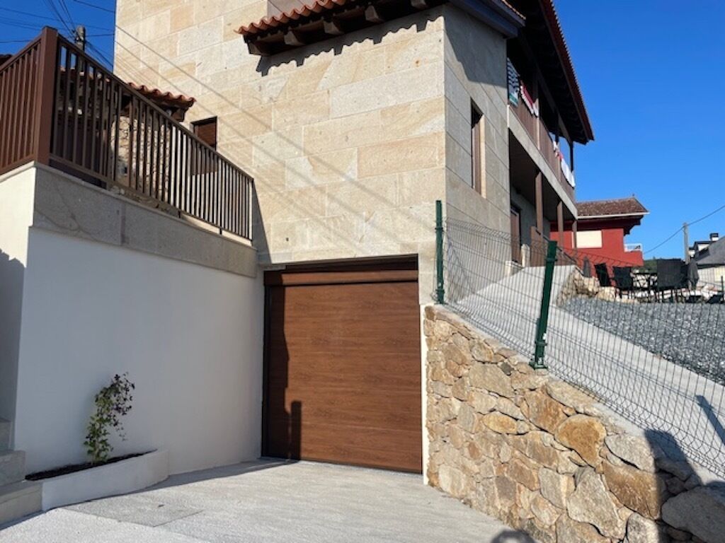 Un edifici amb façana de pedra, una porta de fusta i una petita planta al primer pla.