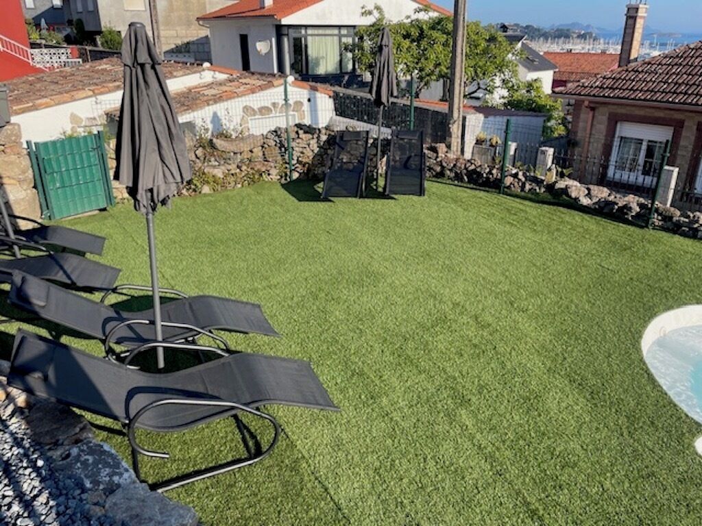 A backyard with artificial grass, a barbecue grill, and outdoor furniture.