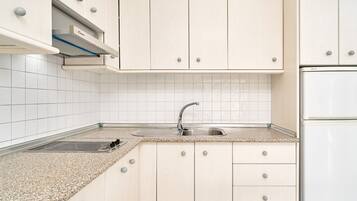 Een keuken met witte kastjes, een roestvrijstalen spoelbak en een inbouwafzuigkap.
