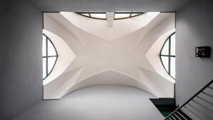 Een modern interieur met een gebogen plafond, dakramen en een trap.