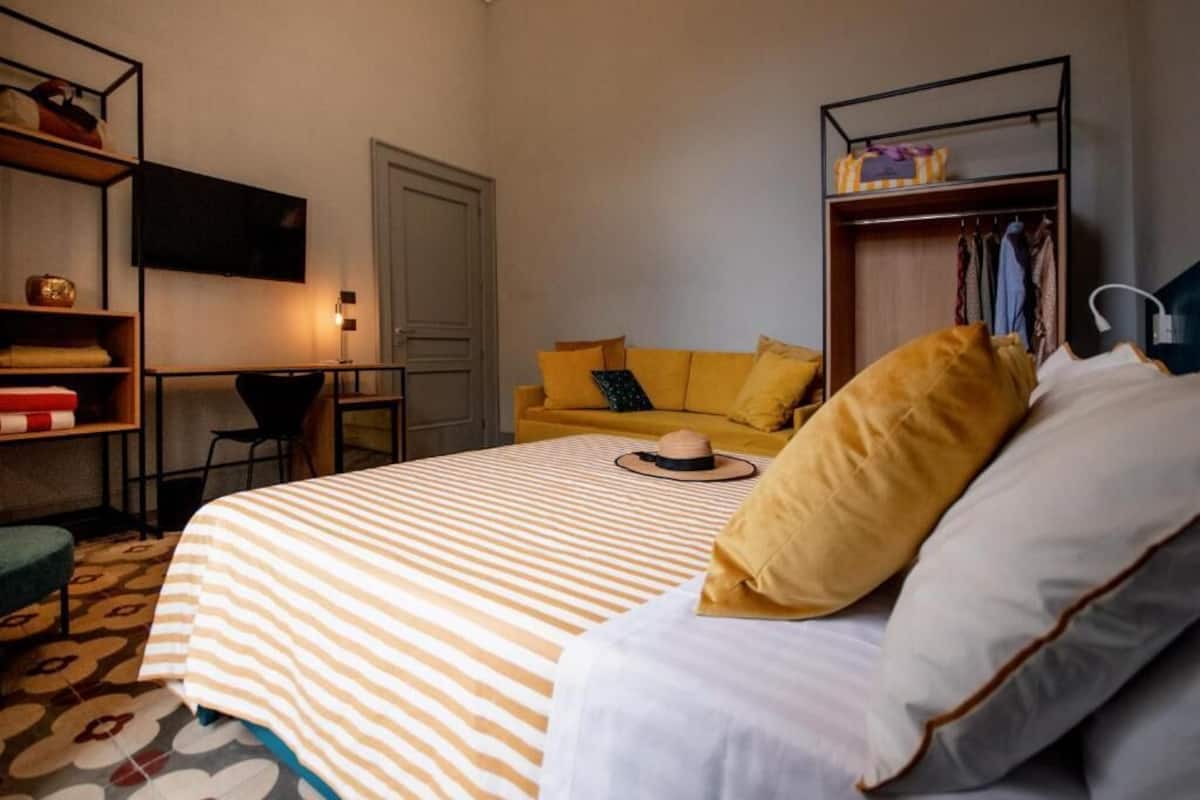 Een slaapkamer met een bed, een bureau, een stoel, een kledingkast en een televisie aan de muur.