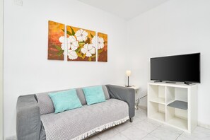 A living room with a sofa, a TV, and artwork on the wall. - Apartment 'N4' with Shared Pool, Wi-Fi and Air Conditioning (Nerja)