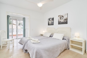 A bedroom with two beds, a chair, a nightstand, and artwork on the walls. - Apartment 'N4' with Shared Pool, Wi-Fi and Air Conditioning (Nerja)