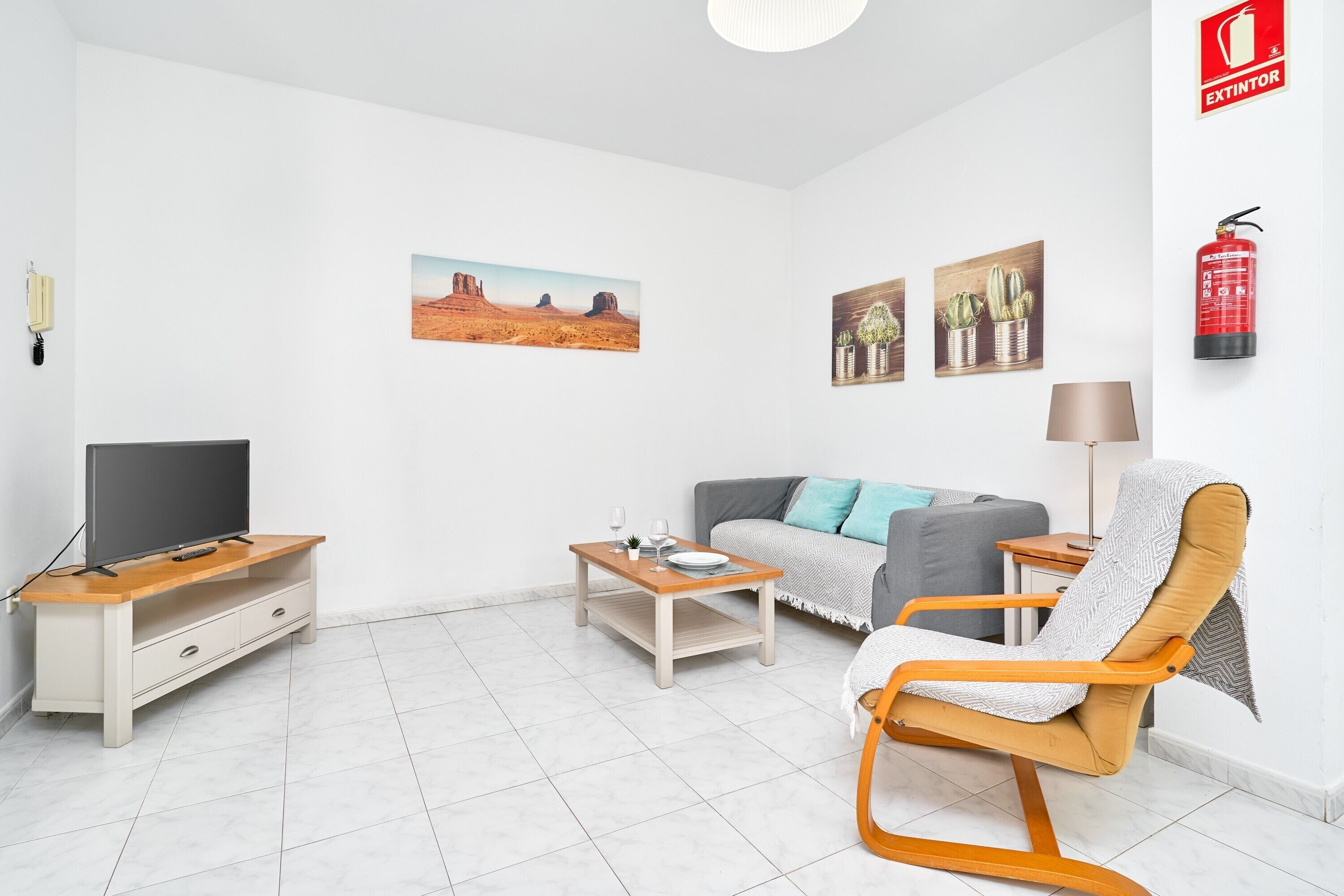 Ein Wohnzimmer mit Fernseher, Sofa, Couchtisch und Sessel.