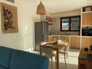 A modern kitchen with a dining area, a large window, and a blue sofa. - Charming 2-bedroom villa with AC in beautiful Sicilia (Sicilia)