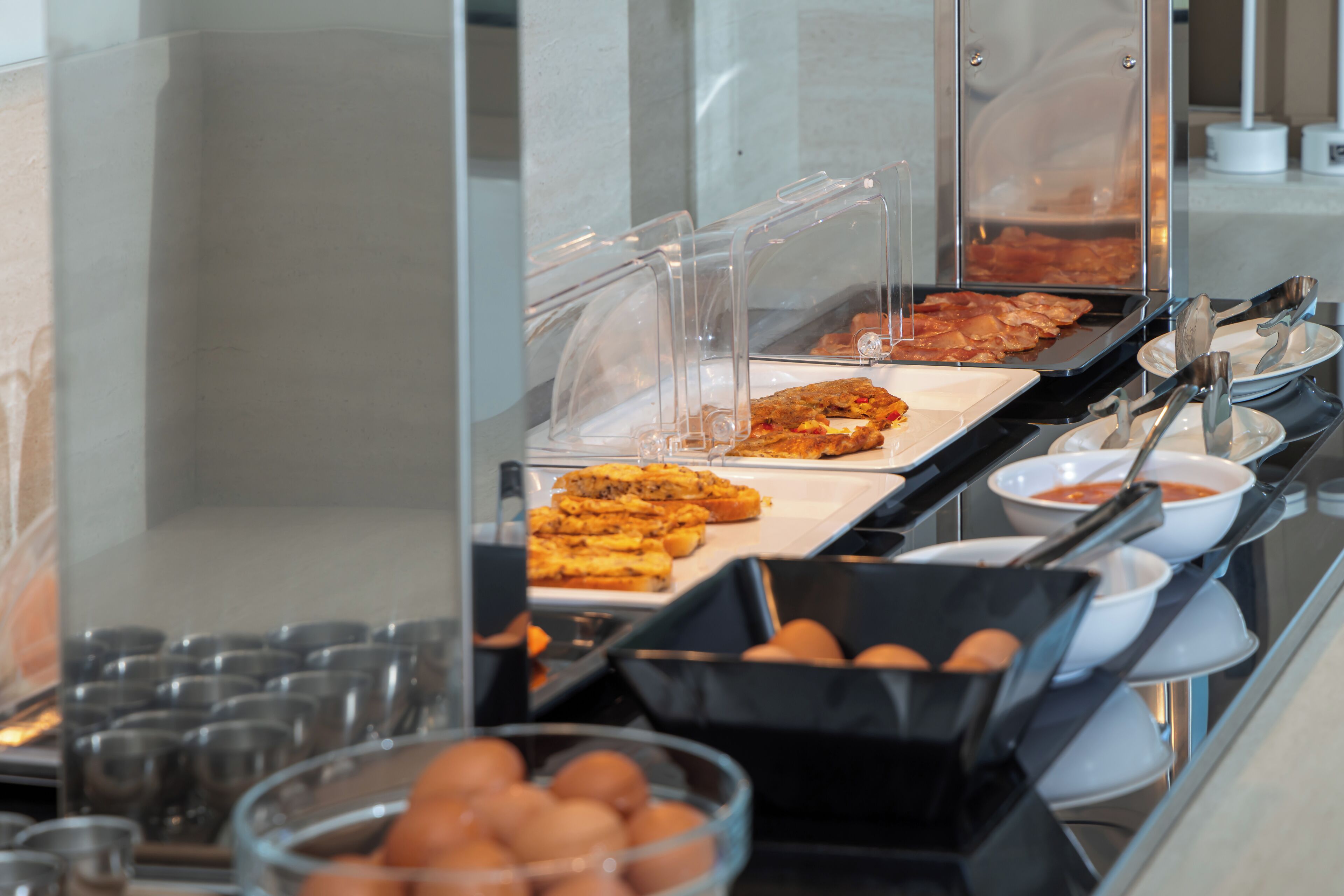 A buffet with various food items, including pastries and a dish with red peppers.