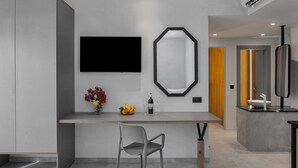 A modern kitchen with a built-in island, a flat-screen TV, a large mirror, and a vase with flowers. - Malia Odyssey Adults Only by Estia (Malia)