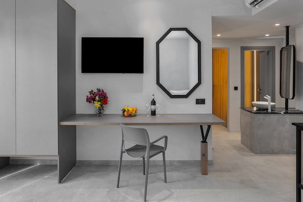 A modern kitchen with a built-in island, a flat-screen TV, a large mirror, and a vase with flowers. - Malia Odyssey Adults Only by Estia (Malia)
