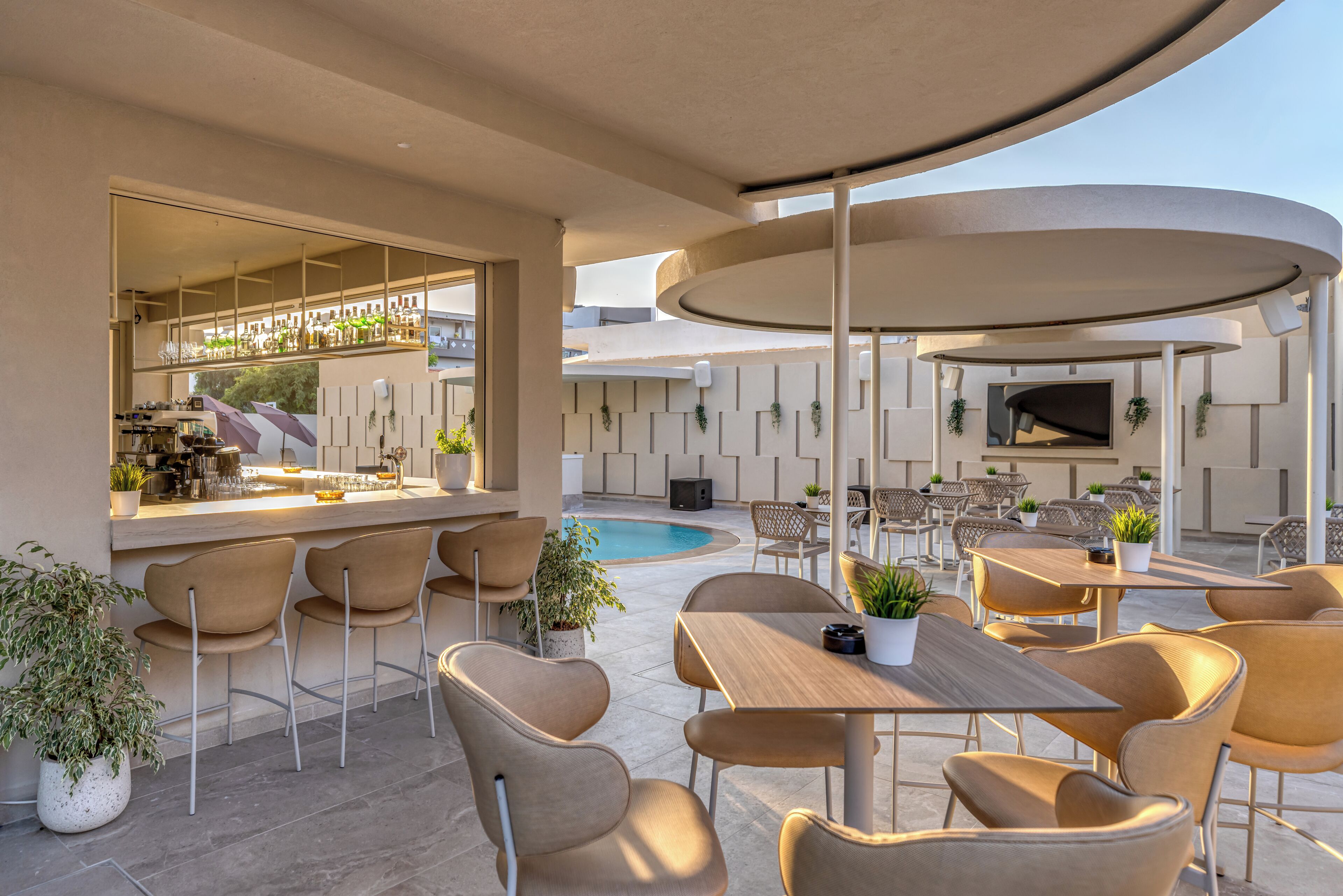 Zona de bar exterior con asientos y piscina.