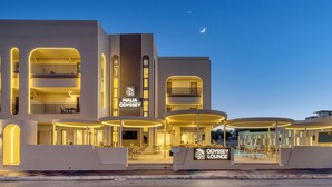 A modern hotel with a prominent 'MALIA ODYSSEY' sign, outdoor seating area, and a pool. - Malia Odyssey Adults Only by Estia (Malia)