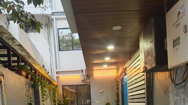 A checkered floor, potted plants, and a chair in a hallway. - Hotel Moon Light Indore (Indore)