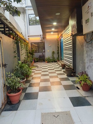 A checkered floor, potted plants, and a chair in a hallway.