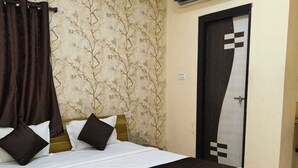 A bedroom with a large bed, an air conditioning unit, a patterned wallpaper, and a door with a geometric design. - Hotel Moon Light Indore (Indore)