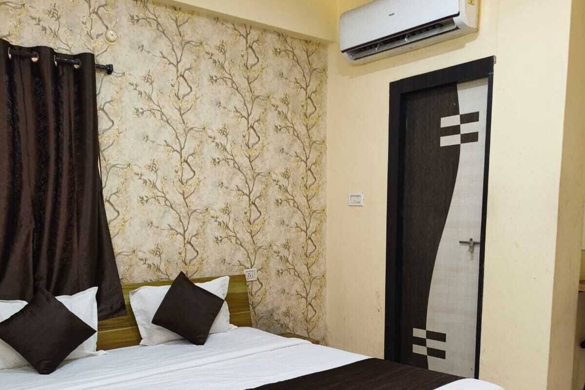 Un dormitorio con una cama grande, un equipo de aire acondicionado, un papel tapiz estampado y una puerta con diseño geométrico.