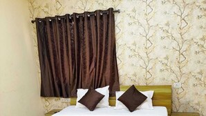 A single bed with a wooden frame, white bedding, and two dark brown pillows. There is a wooden nightstand beside the bed. - Hotel Moon Light Indore (Indore)