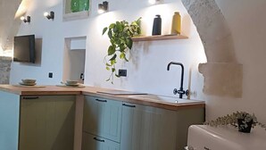A kitchen with a white countertop, green cabinets, a white refrigerator, and a hanging plant. - At Vico 12 (Monopoli)
