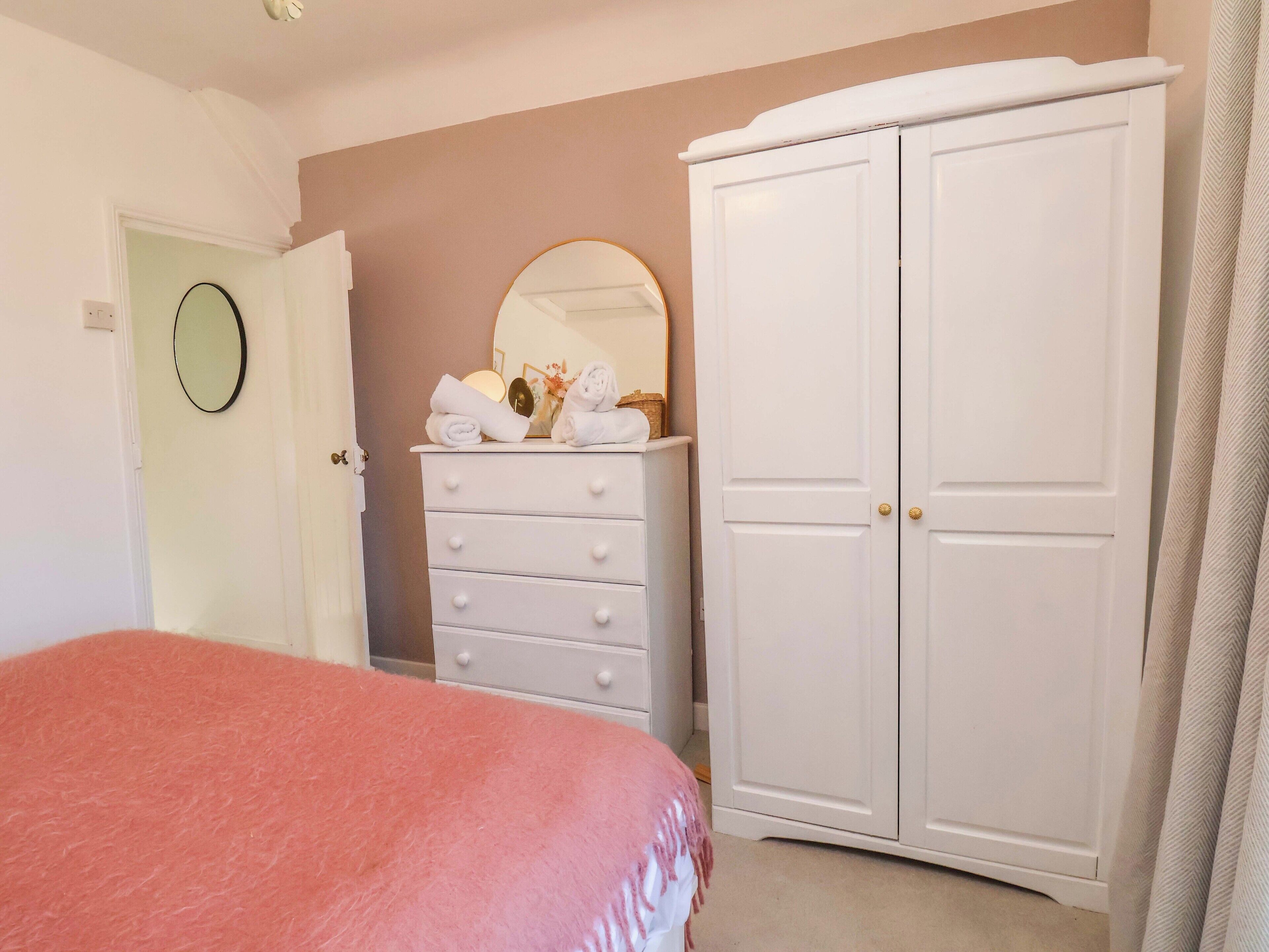 Une chambre à coucher avec un lit, une commode avec des serviettes, une armoire et un miroir.