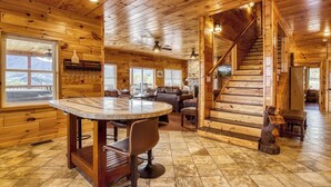 Un interior de madera con una mesa redonda para comer, una escalera y una estatua de oso.