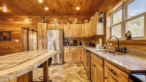 Una cocina con armarios de madera, un refrigerador de acero inoxidable, una encimera de granito y una ventana con vistas.
