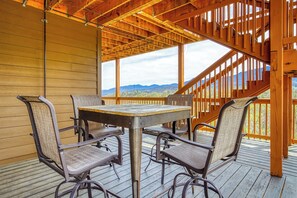 A covered outdoor seating area with a table and chairs, wooden walls, and a view of mountains. - Beartastic Mountain View Lodge, Game Room, Hot Tub! (Gatlinburg)