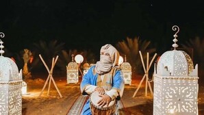 Une personne jouant d’un tambour dans un d écor agrémenté de lanternes décoratives et de détails architecturaux.